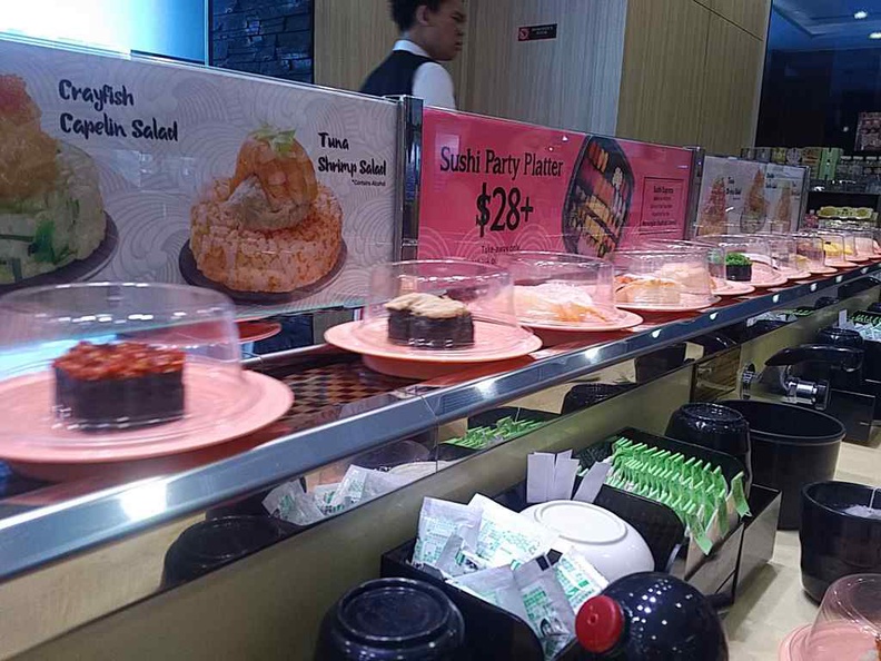 The conveyor belt can get pretty full on peak meal periods. Note the self-help wasabi, sauces and green tea too