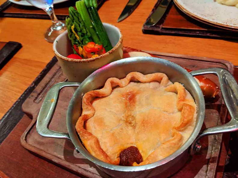 Steak and ale pie with servings of greens
