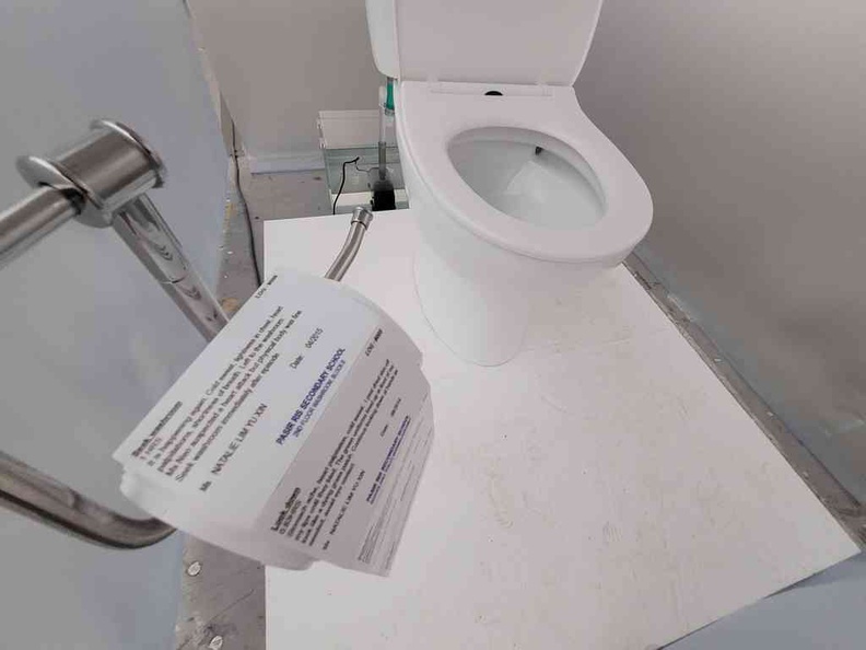 Personal space featuring a flushable toilet and instruction sheet