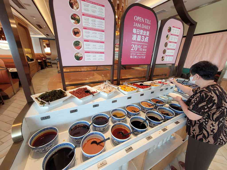 Condiment counter offers a selection of garnish and fruits.