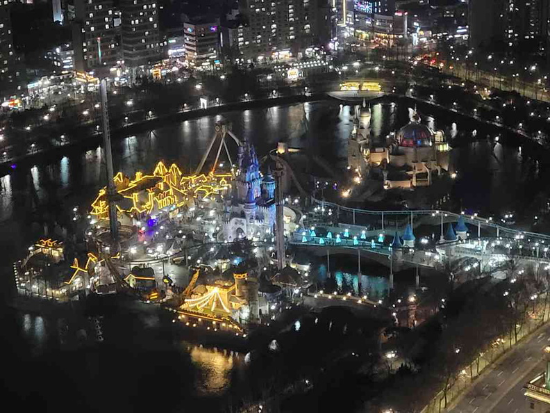 A close up of Lotte World outdoor park with rides lit and operating