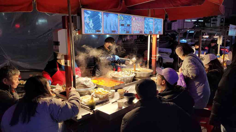 Market crowds with locals enjoying a hot meal at the Myeongdong late night market in Seoul