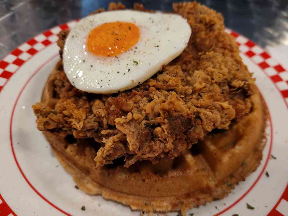 Southern fried chicken on crispy waffles with topped fired egg. 