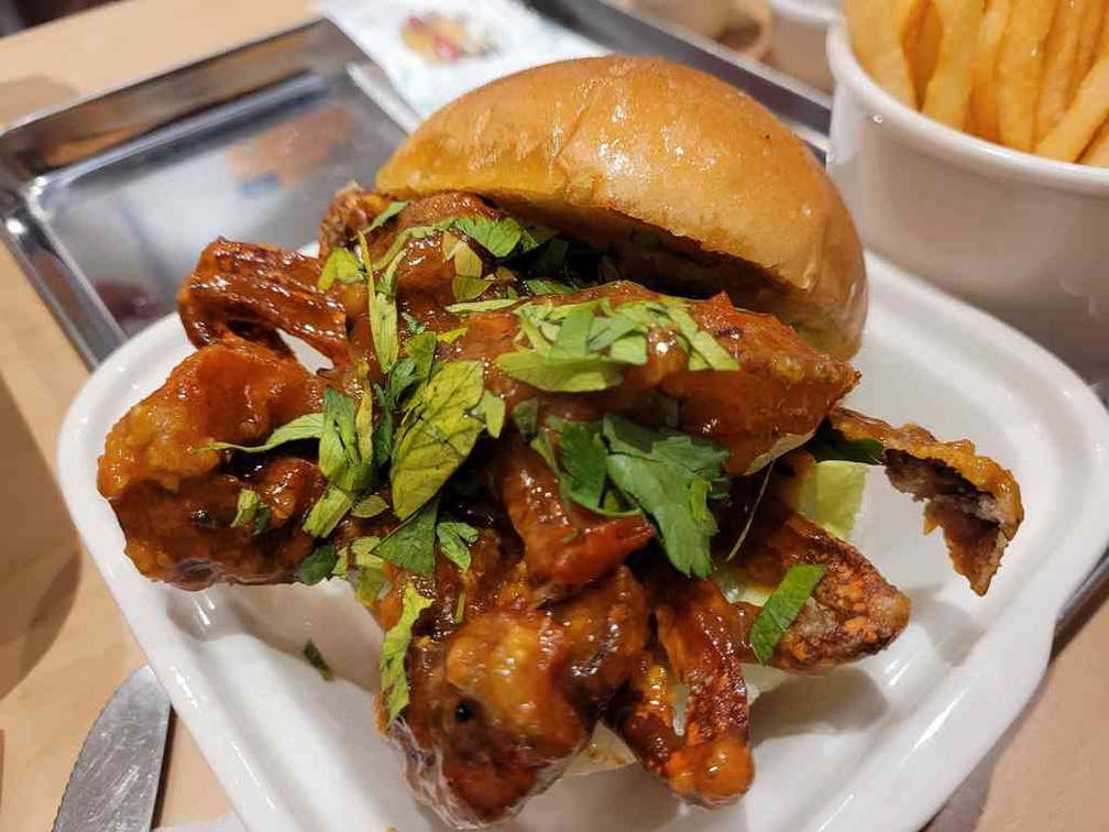 Soft Shell Crab Burger, with the crab humorously spilling out of the burger.