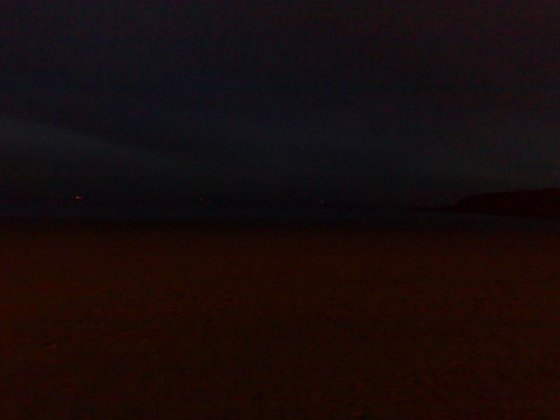The sky and beach seperated by a shoreline in the dark!
